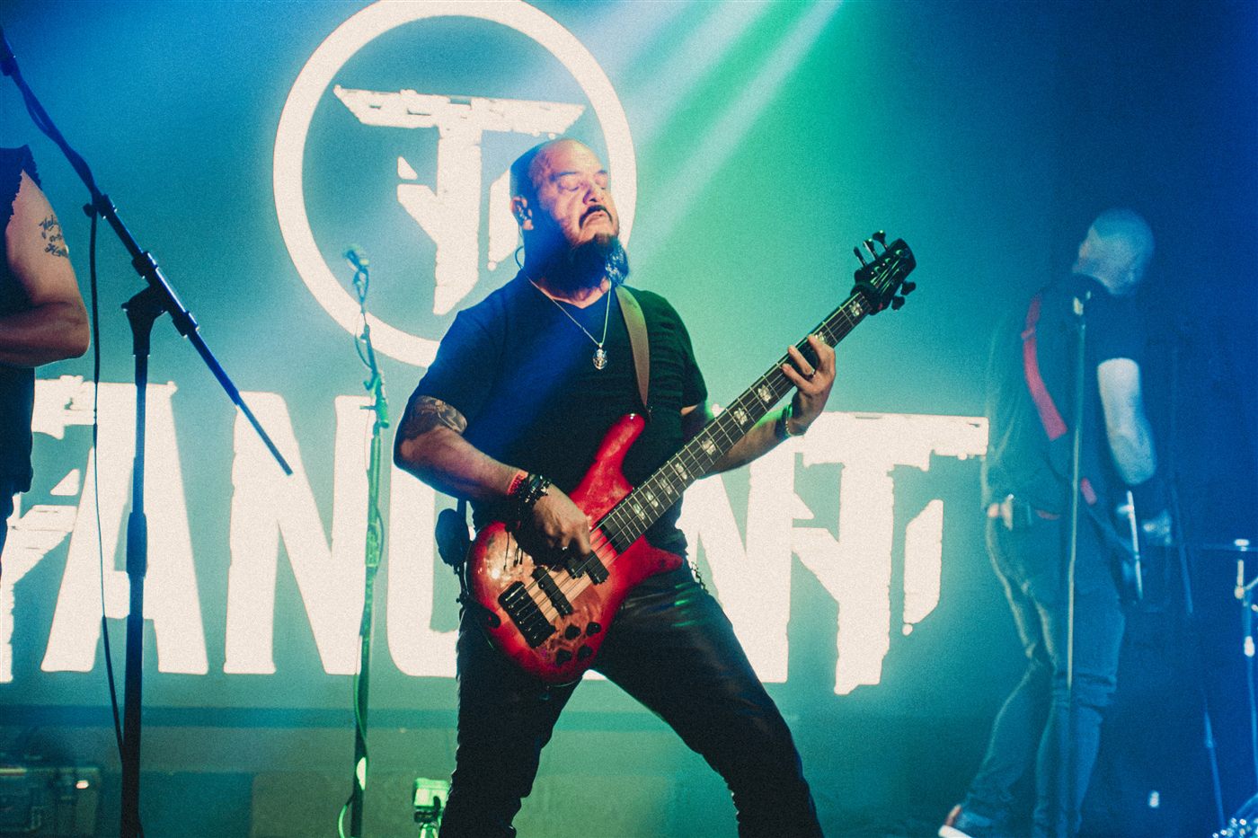 Bassist with a red bass in front of the glowing TangenT logo
