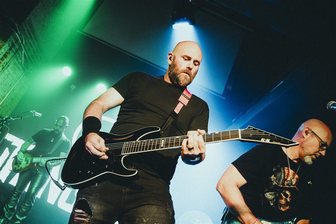 Two guitarists playing side by side under blue and green light