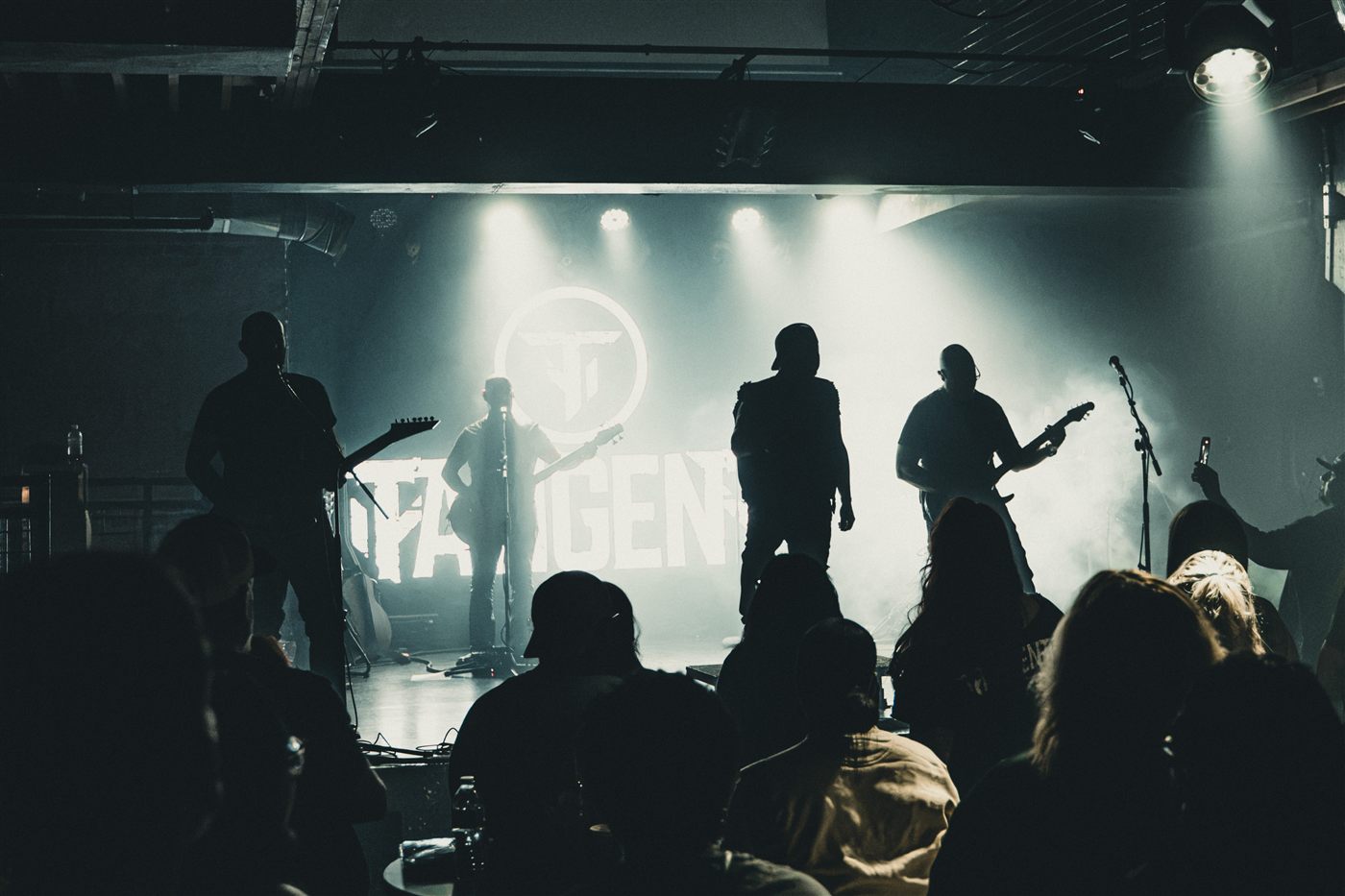 The band in silhouette against the lit logo, with the crowd in front